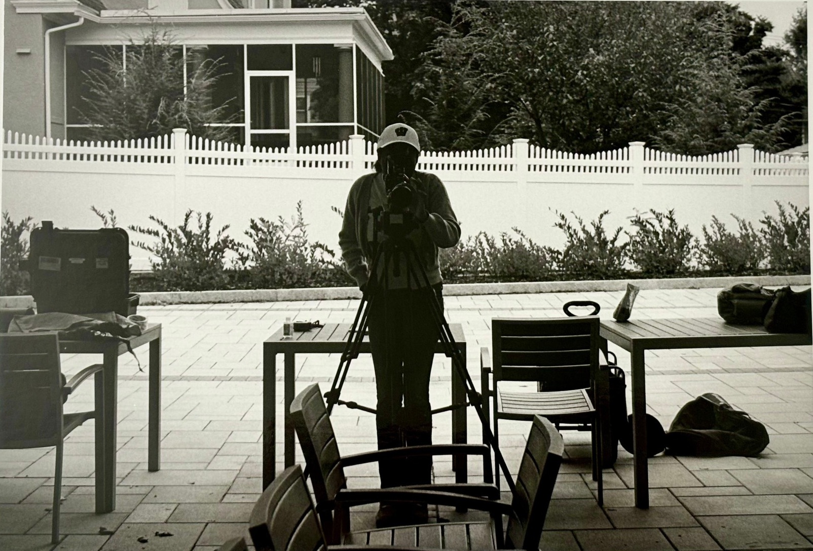A filmmaker and tripod reflected in an outdoor patio