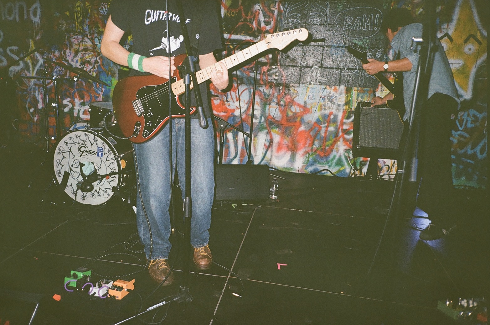 A guitarist performing in a graffiti-covered room